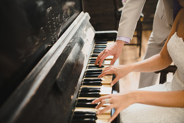 beautiful and romantic picture: the groom and the bride play together on the piano