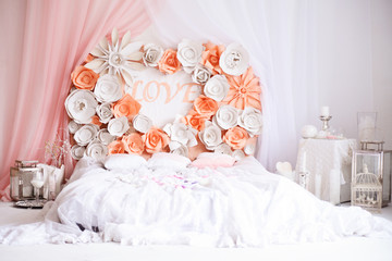 Romantic white with a white bed in the shape of a heart and the inscription love in a bright room. Wedding decor or Valentine's day
