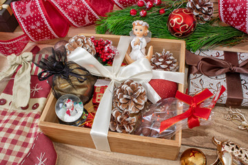 Christmas gifts in a wooden box on a wooden background. Christmas tree branches, decorations, cones, angel and gifts.