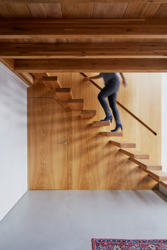 Wooden design stairs in a loft in Amsterdam, The Netherlands. A woman wearing heals is going up the stairs.