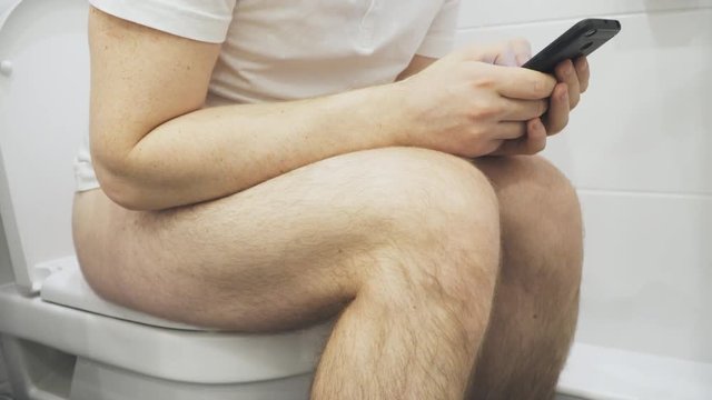 Man using mobile phone in the toilet.