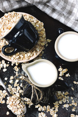 Oat milk in a milk jug on the background of oatmeal. Vegan milk. Eco food.