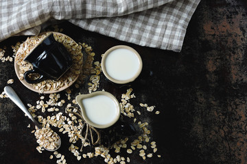 Oat milk in a milk jug on the background of oatmeal. Vegan milk. Eco food.