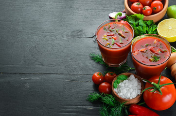 Gazpacho Soup in Glas. Tomato soup with onion, paprika and parsley. Italian cuisine. Top view. On a black background. Free space for text.