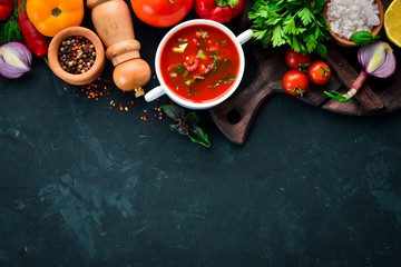 Tomato soup with onion, cucumber and paprika. Top view. On a black background. Free space for text.
