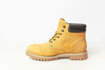 Yellow men's work boots from natural nubuck leather on wooden white background. Trendy casual shoes, youth style. Concept of advertising autumn winter shoes, sale, shop.