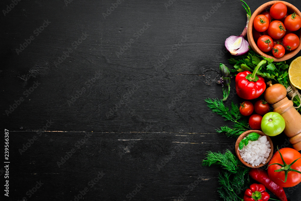 Wall mural vegetable background. fresh tomatoes, paprika, onions and parsley on the table. top view. on a black