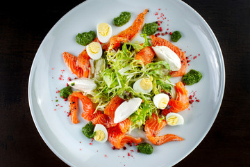 Salad from eggs, greens and trout. On white plate.