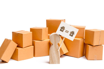 A wooden figurine of a person stands near a pile of boxes and raises the question of how to transport the goods from one house to another. The concept of moving to a new home, transportation companies