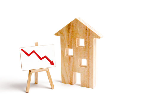 A Wooden house and red arrow down. concept of falling prices and demand for real estate, crisis and recession, the fall in the rate of construction of new housing and buildings. Low quality
