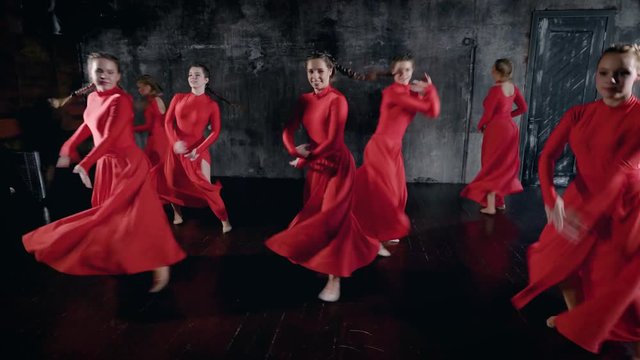 Group of beautiful girls in red dress dancing all together in a studio, group dance rehearsal.