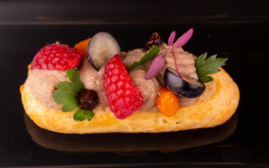 A liver of a guinea fowl on bruschetta with raspberry, grapes and greens