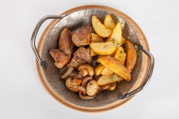 Potatoes with meat and mushrooms in the iron plate