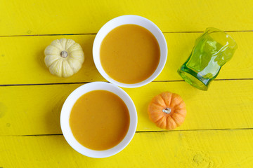 pumpkin soup and pumpkins on a yellow wooden table