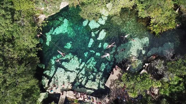 Cenote Azul in the jungle aerial view. People swim in clear water in a cenote that is in the jungle. Top View