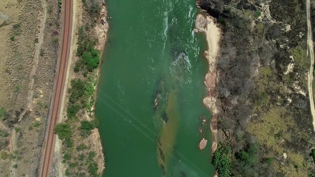 Drone landscape tilt up along the course of the River Doce. Small bridge in the center. In the background mountains and cloudy sky. Atlantic Forest Biome. Video recorded in southeastern Brazil.
