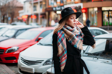 young woman in black coat, hat and scarf. girl walking around the city