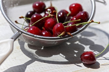 Fresh sweet Cherries on table with water drops macro background. Freshly washed cherry in a colander