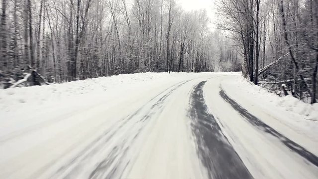 Driving through the winter forest on snowy road, first view. Camera outside the window on steadicam. Driving pov at the first snow of winter on a beautiful mountain fir forest road.