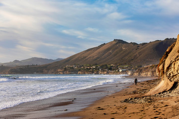 Fototapeta na wymiar Surfer walking along the beach