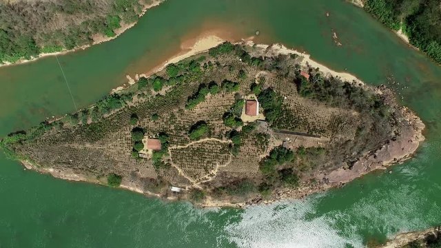 Drone zoom out over island in the middle of the river Doce. Trees and small houses below. Landscape of Atlantic Forest Biome. Video recorded in southeastern Brazil.
