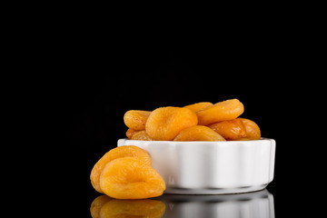 Dried Apricots in bowl Isolated on reflective black background, copy space