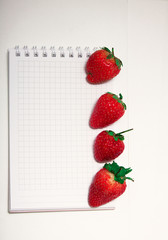 Healthy Food Vitamin Concept. Delicious strawberry on board on white background with empty paper notebook.