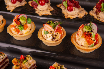 Tartlet with shrimps and fresh vegetables with red caviar and greens