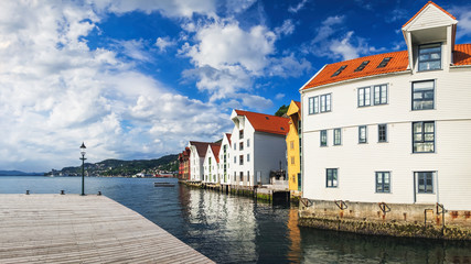 Naklejka premium Historical buildings in Bryggen - Hanseatic wharf in Bergen, Norway. Scenic summer panorama with the Old Town pier architecture and large cruise ship in the port