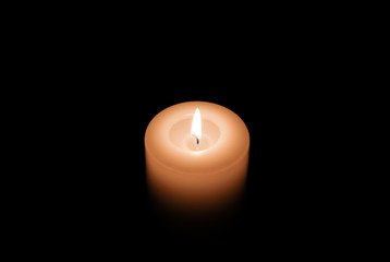 A white burning candle in the dark. 