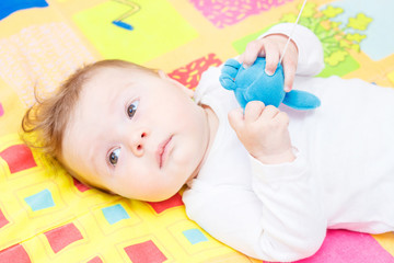 Playing little child on the colored mat for developing