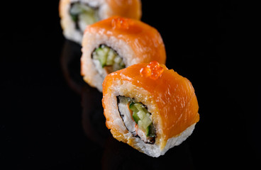 Delicious and appetizing sushi with red fish on black acrylic with reflection. Sushi close up.