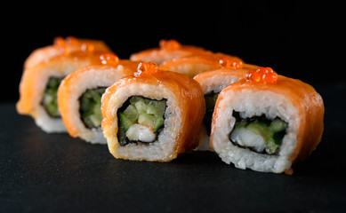 Delicious and appetizing sushi with red fish on black acrylic with reflection. Sushi close up.