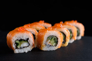 Delicious and appetizing sushi with red fish on black acrylic with reflection. Sushi close up.