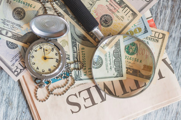 Pocket clock, American dollars and a magnifying glass
