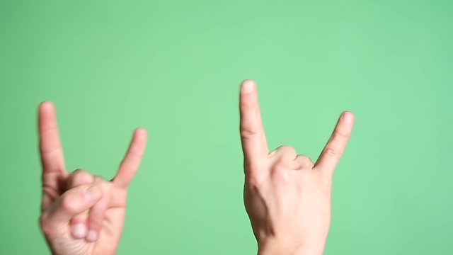Hands gesturing heavy metal rock sign isolated green screen