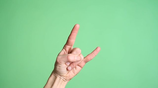 Hands gesturing heavy metal rock sign isolated green screen