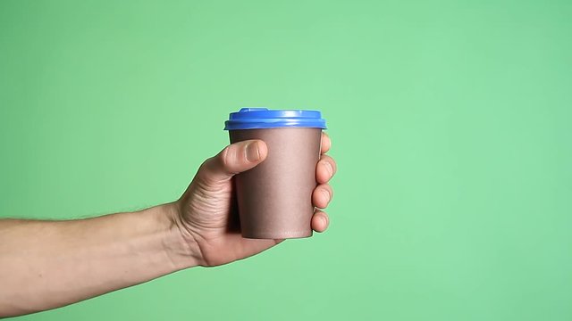 Hand holding coffee cup on green screen background