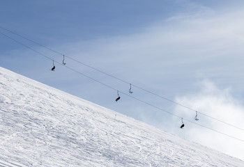 Snowy off-piste ski slope with traces from skis and snowboards and chair-lift