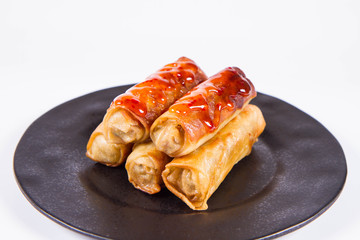 Chinese Traditional Spring rolls with sweet and sour sauce on a black plate