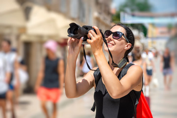 Tourist with a camera photographing the streets on a sunny day.