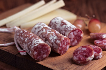 Spanish cheese and fuet on wooden board, dim light