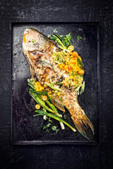 Traditional BBQ parrotfish with mango salsa as top view on a black board
