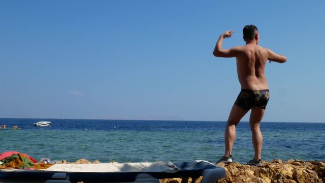 Young crazy man dancing on beach with marine sea surface background