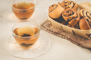 two glass tea and roll with poppy in a wooden basket/two glass tea and roll with poppy in a wooden basket on a white marble table