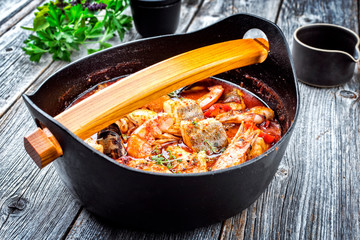 Traditional Catalan sarsuela seafood stew with prawns, mussels and fish as top view in a modern design Japanese cast-iron roasting dish