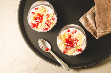 yogurt with pomegranate and flakes on a black tray/Homemade yogurt with pomegranate and flakes on a black tray, top view