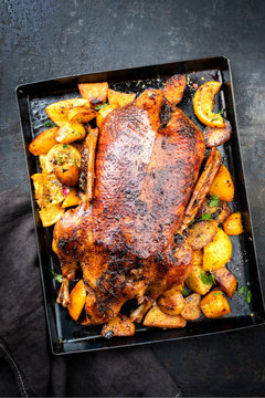 Traditional roasted Christmas duck with fruits and potatoes as top view on a board