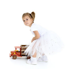 Little girl is playing with a wooden car.
