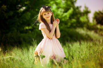 Fototapeta na wymiar Portrait of beautiful little girl in elegant dress in green summer field